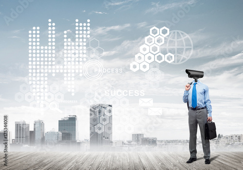 Camera headed man standing on wooden floor against modern cityscape