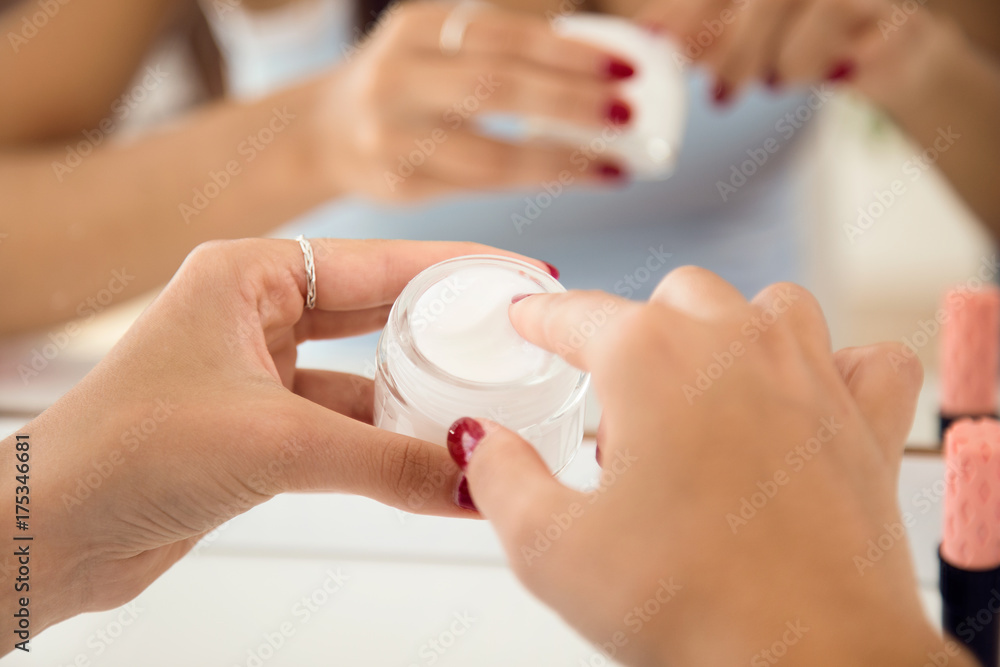 Beautiful young woman caring of her skin near mirror in the bathroom. Beautiful young woman caring of her skin near mirror in the bathroom.