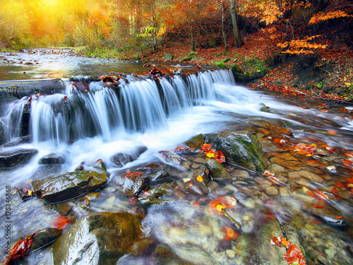 Mountain river with rapids and waterfalls at autumn time