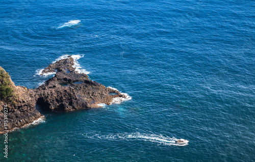 Pleasure motor boat goes near coastal rocks photo