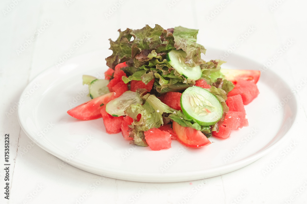 Green salad with cabbage, tomatoes and cucumber on the white plate