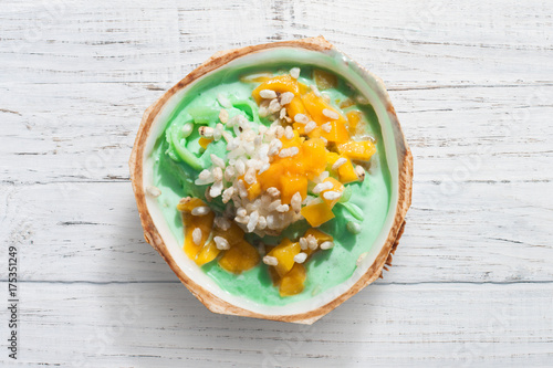 Green smoothie in the coconut bowl with mango, ice-cream and cereals