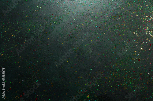 Festive backdrop for Christmas greeting. Top view of black background with holiday sparkles and green glitters, free space. Celebration, presents and congratulation concept