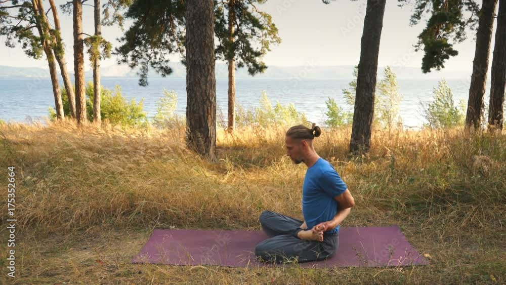 young man doing yoga in the woods by the river young man doing yoga in the woods by the river