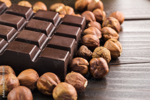 Part of bitter dark chocolate bar with hazelnut on wooden planks background, close-up view