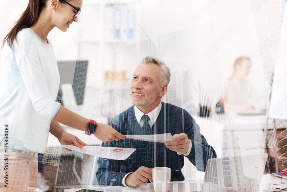 Obraz premium Cheerful professional man working in the office with his young colleague