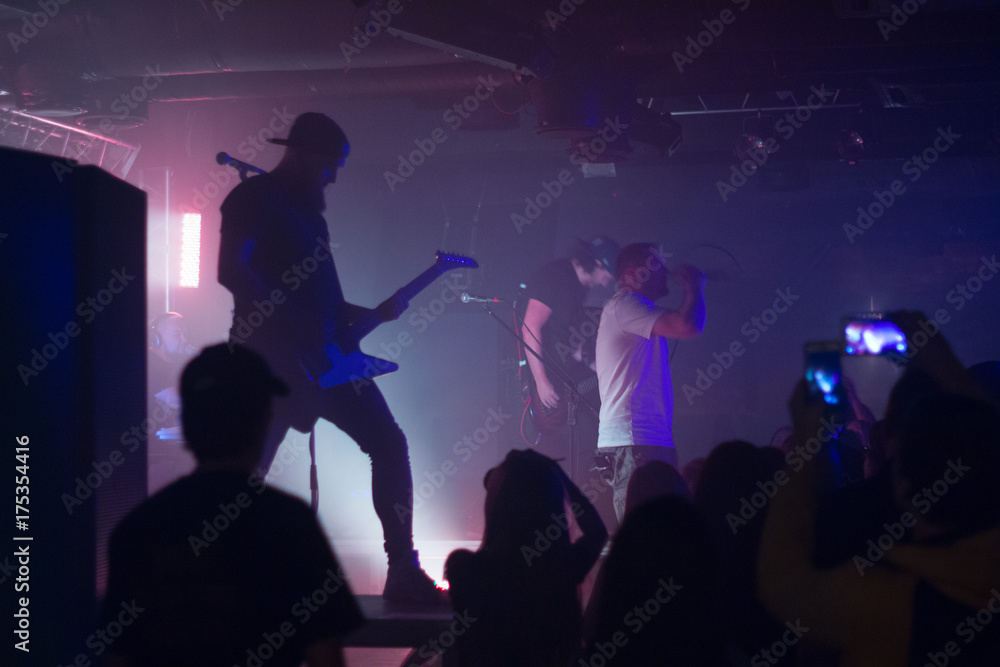Fototapeta premium Guitarist on a stage playing rock to the crowd of people.