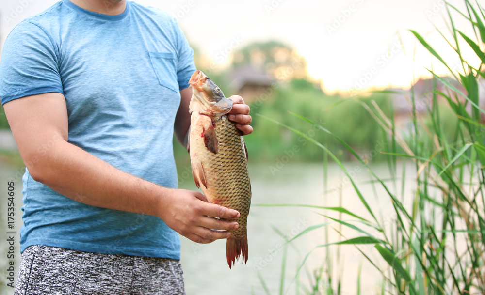 Man with freshly caught fish on river bank