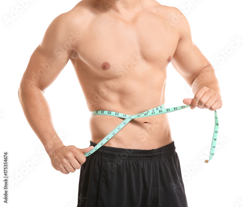 Sporty young man with measuring tape on white background