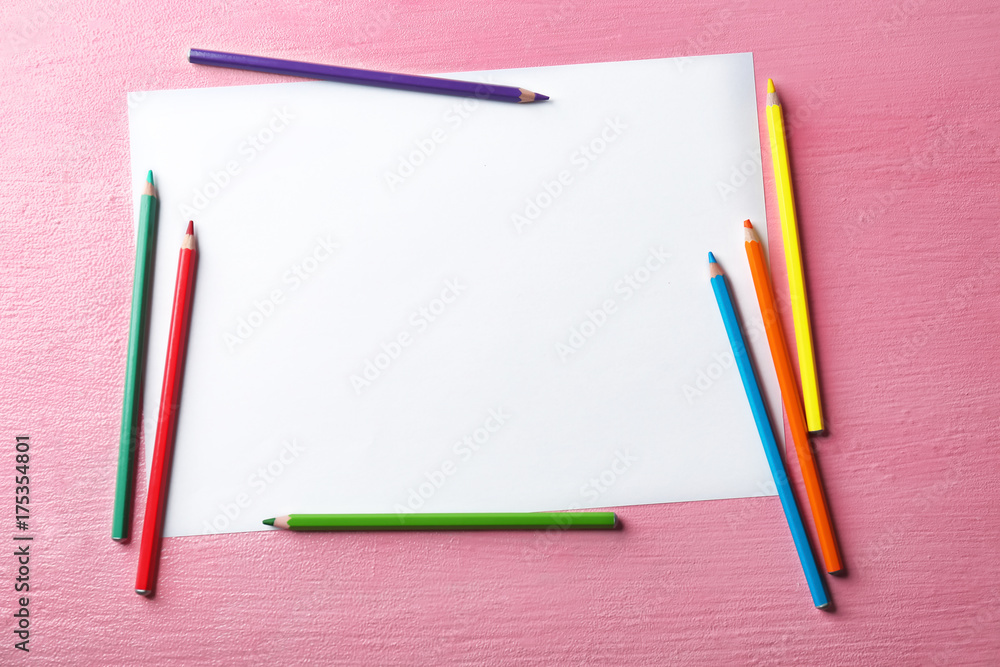 Blank sheet of paper and color pencils on pink background Blank sheet of paper and color pencils on pink background