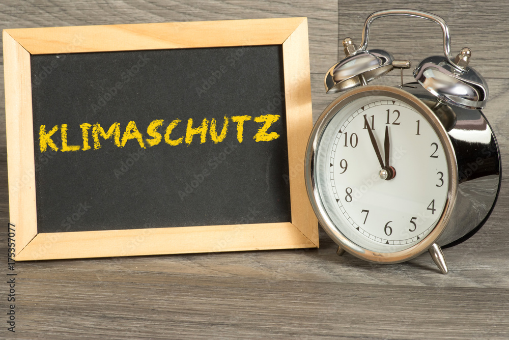 Ein Wecker und Kreidetafel mit dem Wort Klimaschutz