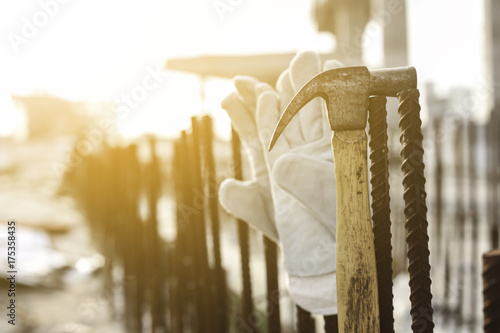 Leather safety gloves and hammer on construction working site background