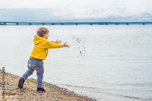Young boy throwing stones in sea water photo