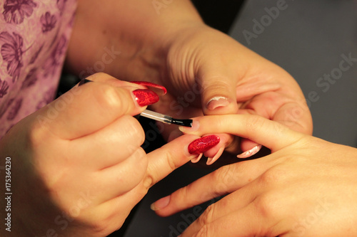manicurist at the training courses of manicure prepares the hand of the client before applying shellac. applying a transparent base