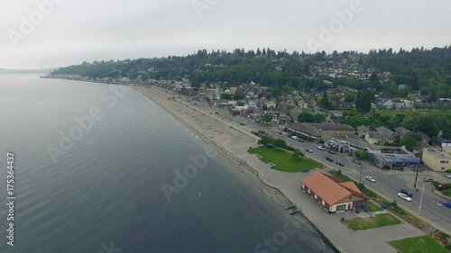Early mourning Alki beach in Seattle, aerial shot of waterfront city with birds flying by the beach, establishing shot
