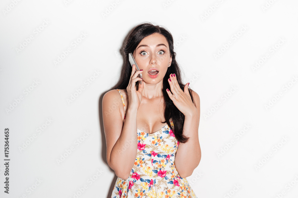 Shocked brunete woman in dress talking by the smartphone Shocked brunete woman in dress talking by the smartphone