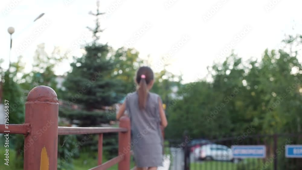 A little girl with a spinner in her hands is walking in the courtyard of the house. A little girl with a spinner in her hands is walking in the courtyard of the house.