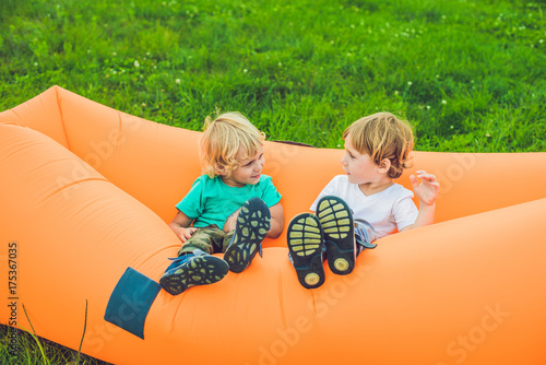 Two cute boys resting on an air sofa in the park. photo