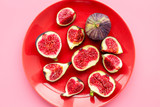 Plate of fresh blue figs on pink background top view