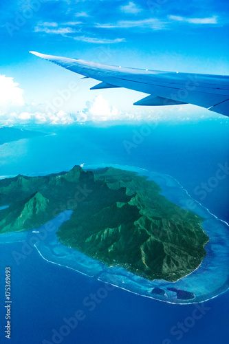View from plane window flying over Moorea island, Tahiti, French Polynesia. Exotic luxury vacation flight travel. Tropical paradise destination.