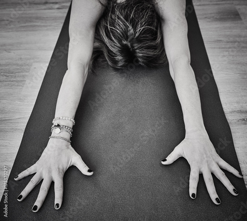 Beautiful young woman working out indoors doing forward bend yoga photo