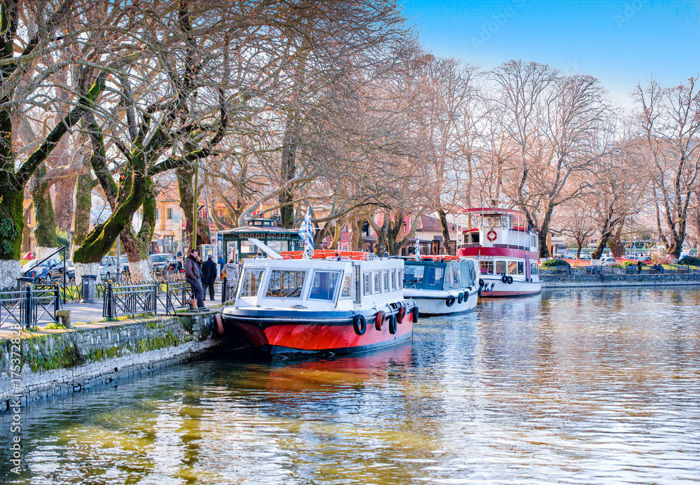 Naklejka premium Ioannina, Pamvotida lake on Autumn.Sunset on lake Pamvotis with docked boats ready to transfer people to the small island, Epirus,Greece