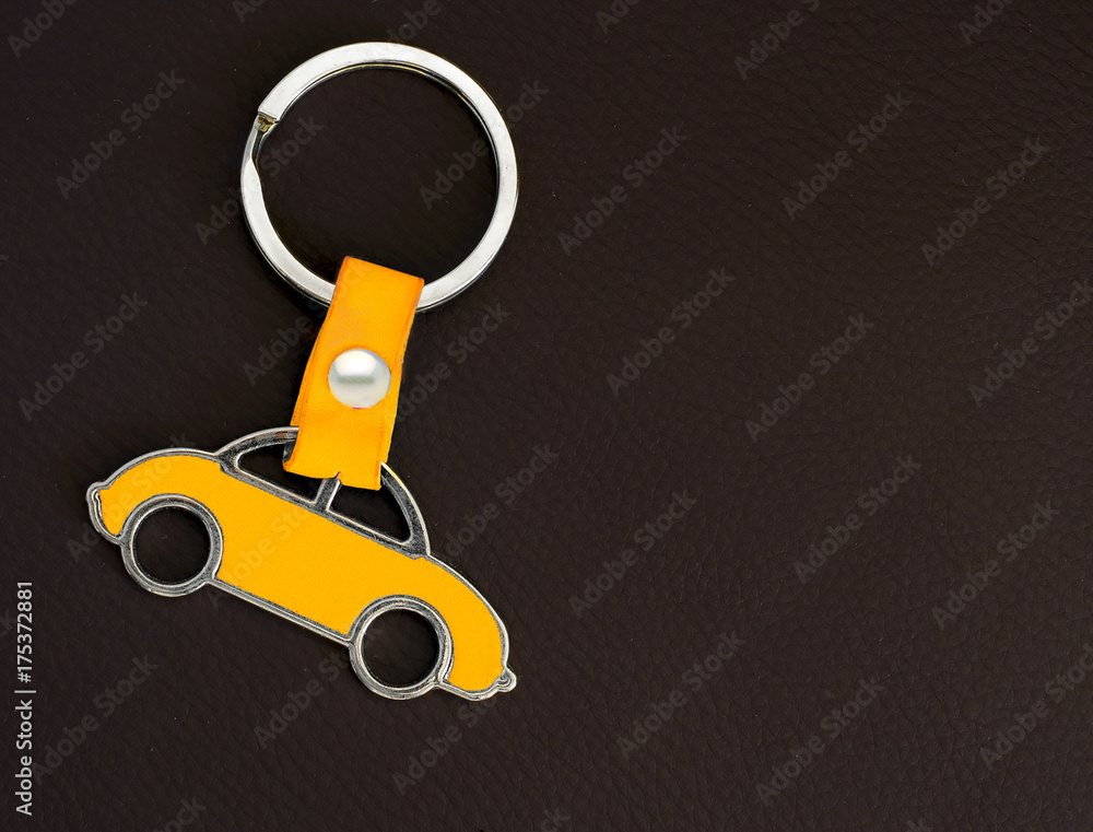 Key chain with a yellow beetle car on dark leather pad as background Key chain with a yellow beetle car on dark leather pad as background