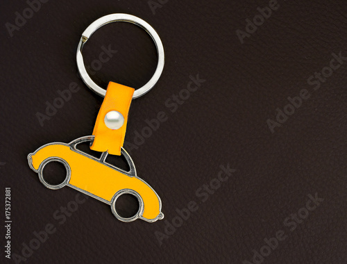 Key chain with a yellow beetle car on dark leather pad as background