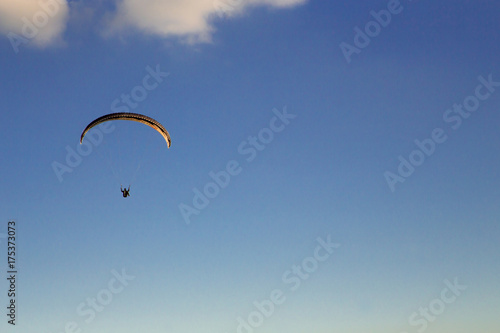 Paraglider flies in the blue sky.