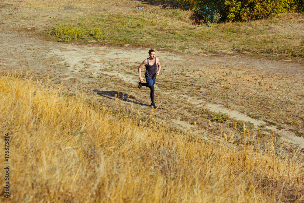 Running sport. Man runner sprinting outdoor in scenic nature. Fit muscular male athlete training trail running for marathon run.