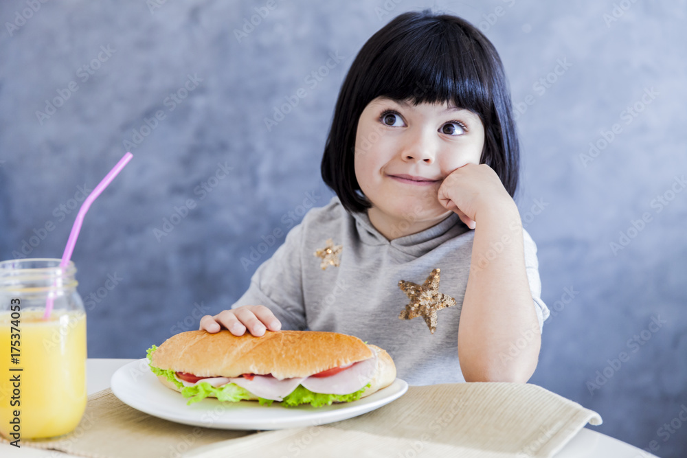 Cute black hair little girl eating sandwich at home Cute black hair little girl eating sandwich at home