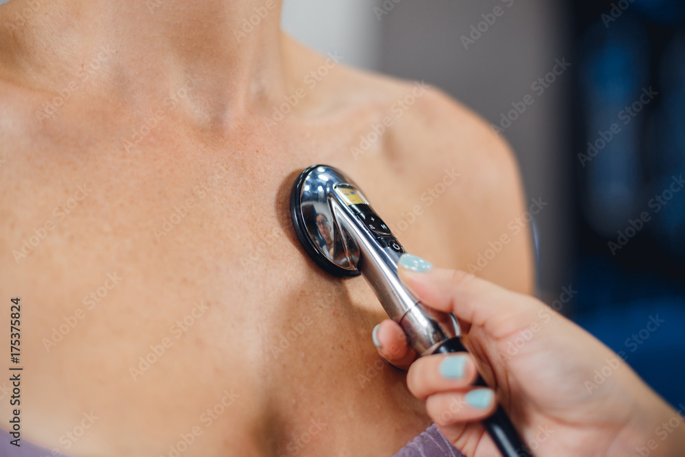 Fototapeta premium Close up view of doctor's hand examining woman patient's heart health checkup using stethoscope in medical clinic.