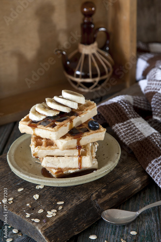 Homemade wafers with fruits, blueberries and sweet vanilla sauce on rustic wooden table. Selective focus, small depth of field, close up photo