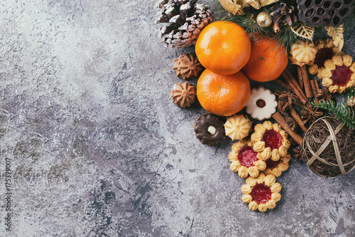 A set of Christmas decorations with tangerines, cookies over a stone background. Top view