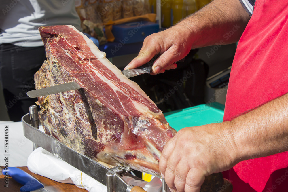 Slicing dry-cured ham prosciutto on the street market