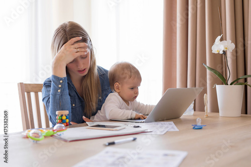 Tired working mom with child in her lap feeling exhausted photo