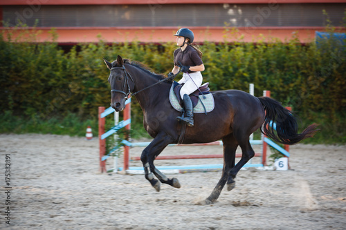 Horsewoman is riding on the competition outdoors © castenoid