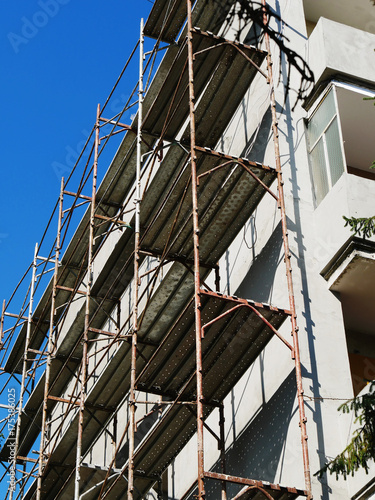 Block of flats undergoing exterior renovation work.  
Metallic scaffolding is raised near building wall. photo