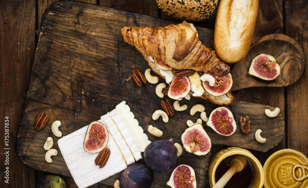 breakfast. a croissant with figs and honey. brie cheese and nuts. wooden board. Vintage background. brown photo. family breakfast. homemade baking