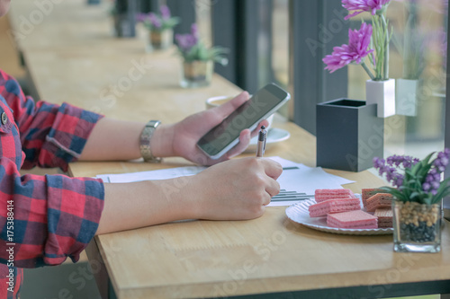 Close Up businessmen working at a coffee shop with a document with a smartphone and a laptop computer Vintage effect.