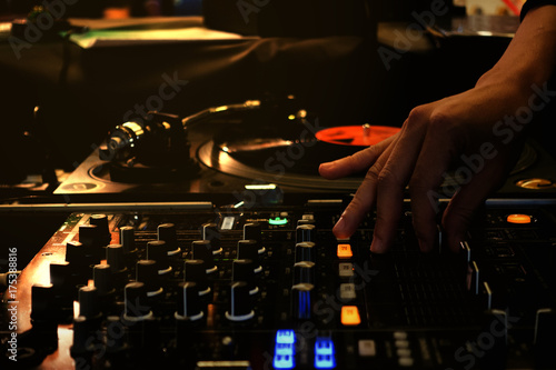 Colorful with hand adjust mixer drop beat by turntable DJ party at nightclub with lowkey and soft focus