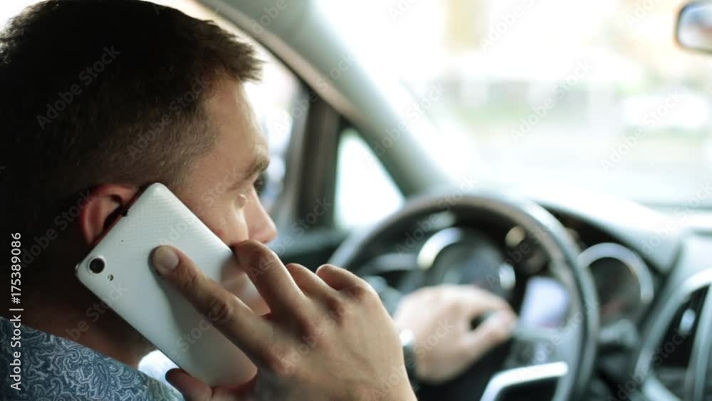 A man in the car is talking on the phone