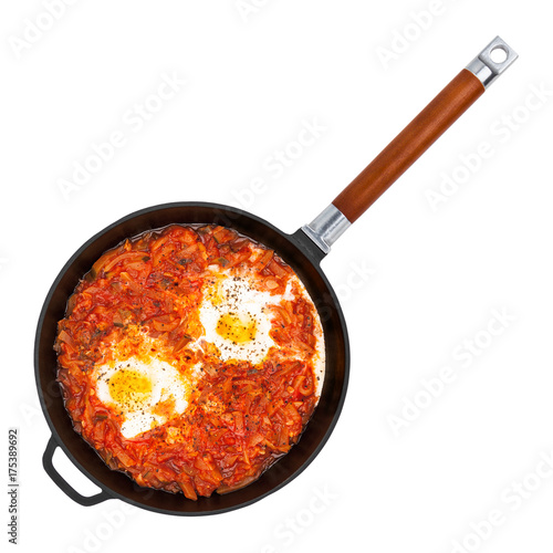 Hot shakshouka in a cast iron pan isolated on white background, top view