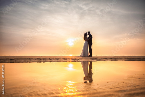 Bride and groom, newlyweds, honeymoon on the beach sunset sun photo