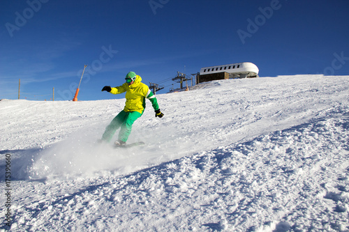 Small snowboarder on blue sky backdrop.
