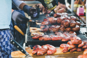 Street food in Amsterdam on sunday market. The cook is doing toasts with fried sausages and mustard.