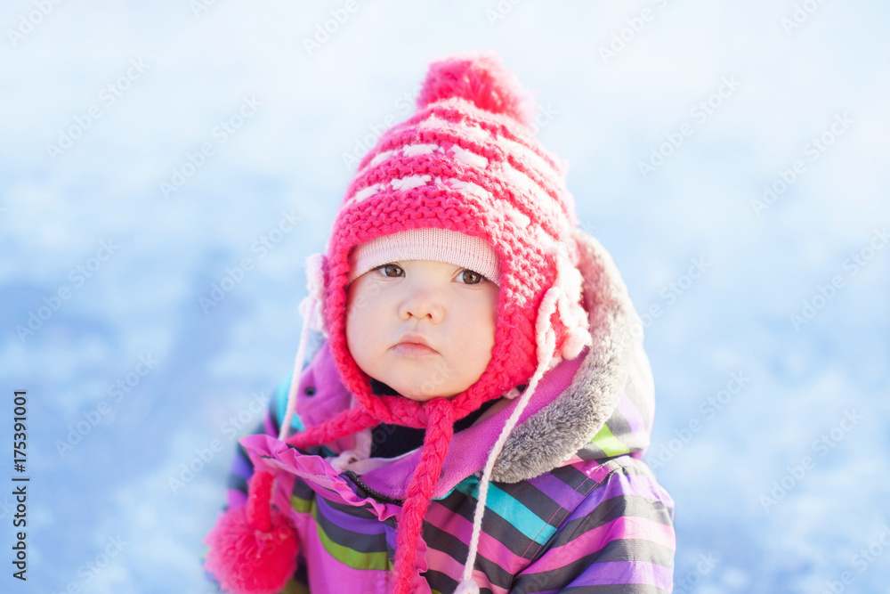 Little cute toddler girl outdoors on a sunny winter day.
