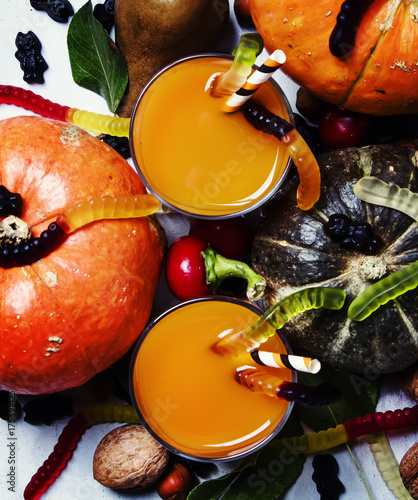 Fresh pumpkin smoothies on Halloween background with black candy, top view