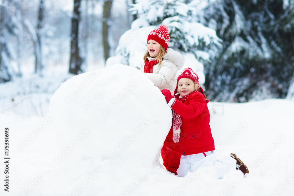 Kids building snowman. Children in snow. Winter fun.