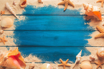 beach scene concept with sea shells and starfish on a blue wooden background